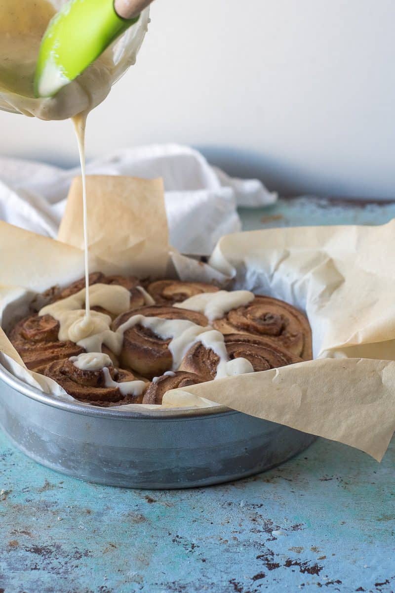 Coffee Cardamom Morning Buns with Creme Fraiche icing getting drizzled on top
