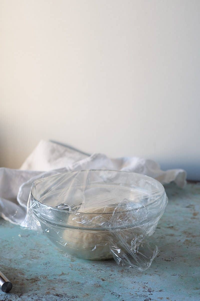 Morning bun dough in a bowl covered with plastic wrap, proofing
