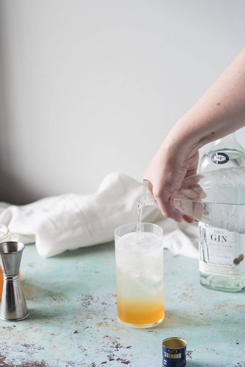 Pouring sparkling water over tonic syrup to make tonic water