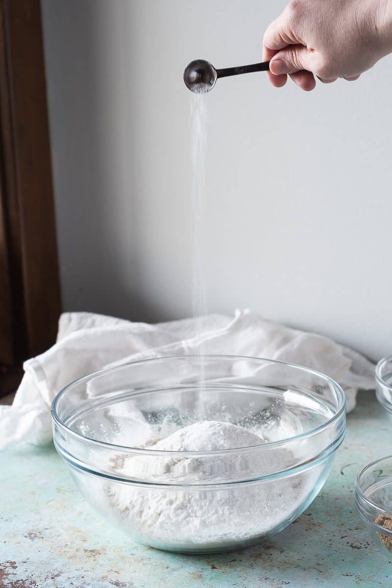 Adding kosher salt to a bowl of dry ingredients