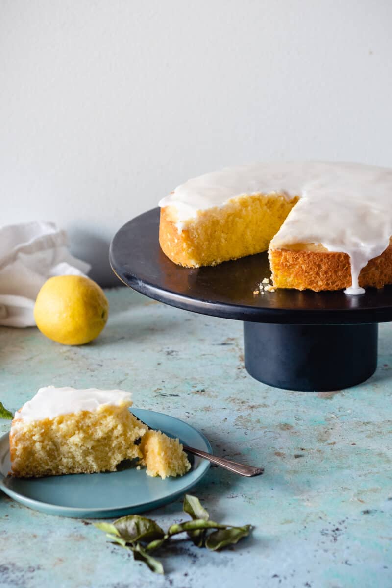 Makrut Lime Leaf Cake on a black cake stand with a slice of cake on a plate alongside it