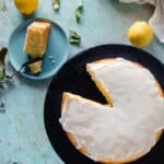 Overhead view of makrut lime leaf cake with lime leaves and lemons scattered around the counter