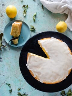 Overhead view of makrut lime leaf cake with lime leaves and lemons scattered around the counter