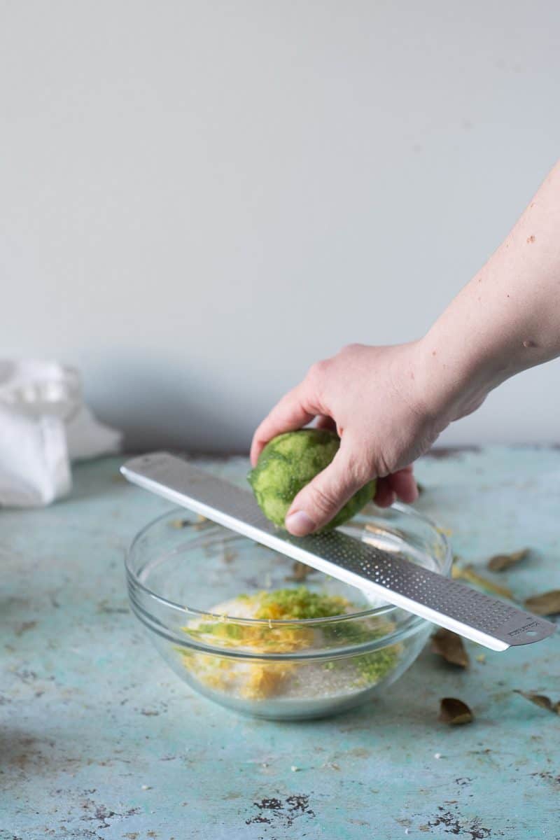 Lime being zested over sugar into a bowl