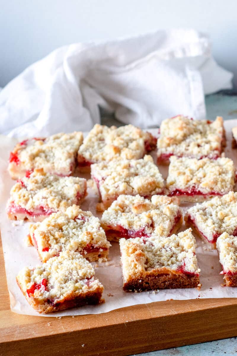 Sliced strawberry crumb bars, side view, on a cutting board