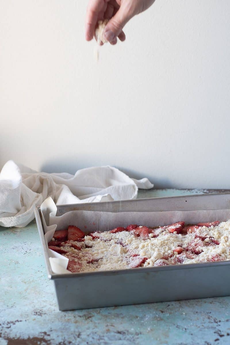 Crumb topping getting sprinkled over the strawberries