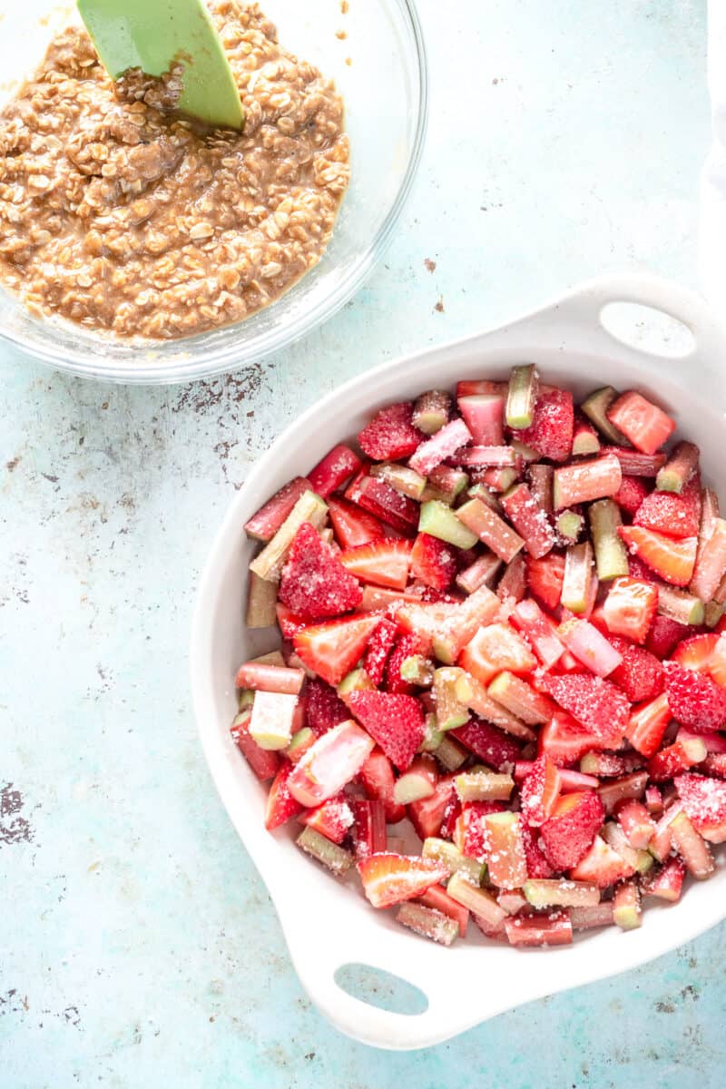 Oat flour crisp batter next to strawberry-rhubarb and sugar mixture in a baking dish