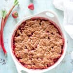 Oat Flour Strawberry Rhubarb Crisp in a baking dish with strawberries and rhubarb stalks nearby