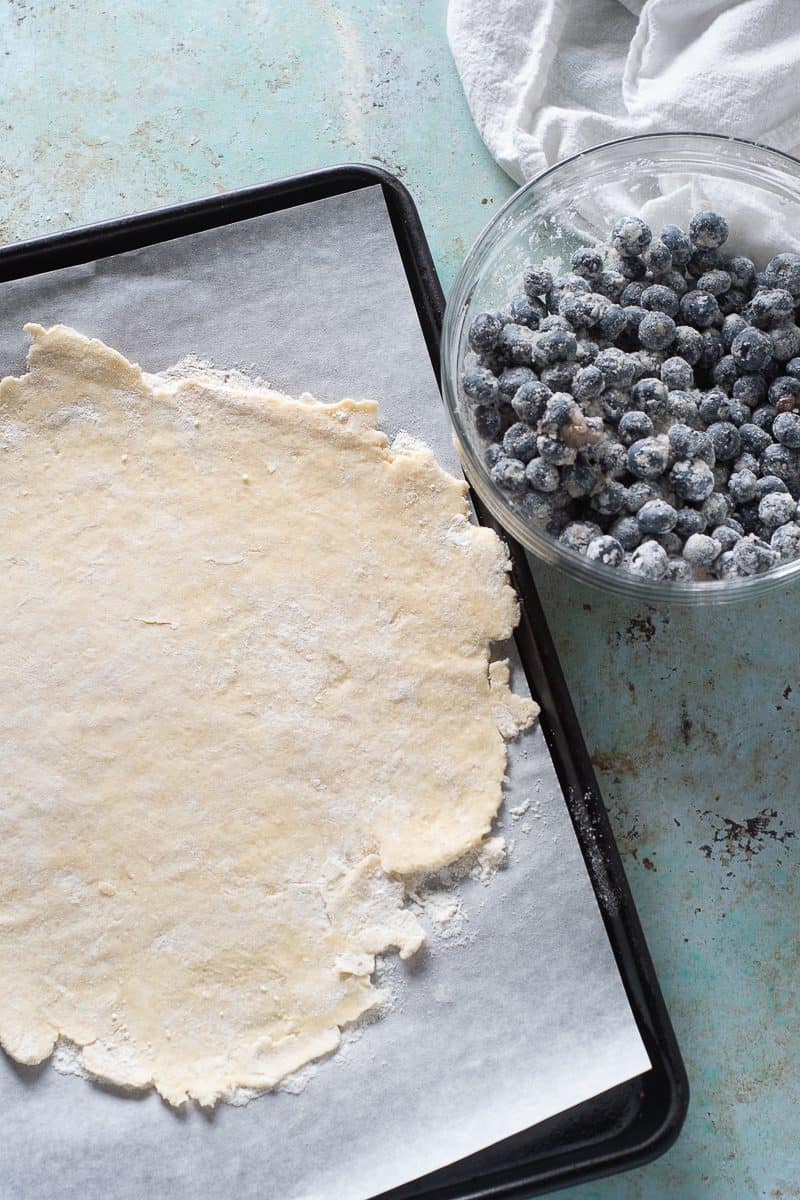 Rolled out galette dough and blueberry filling in a bowl