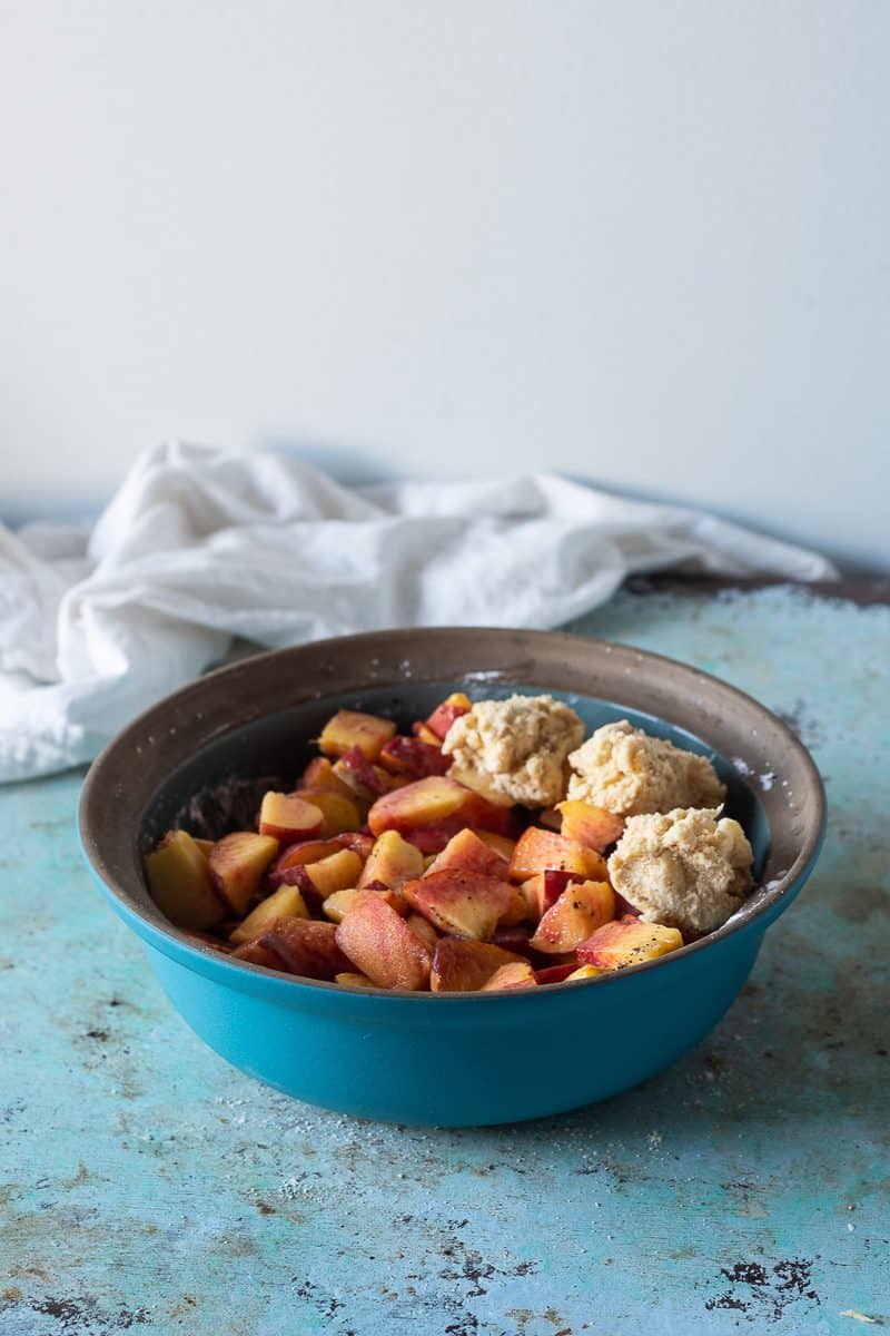 Adding biscuit dough to the peaches and sugar