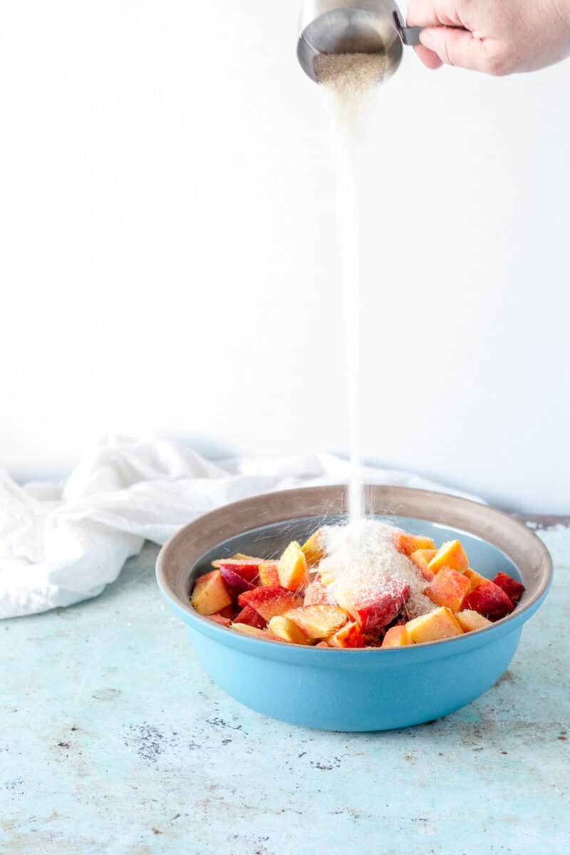 Sugar being poured over sliced peaches