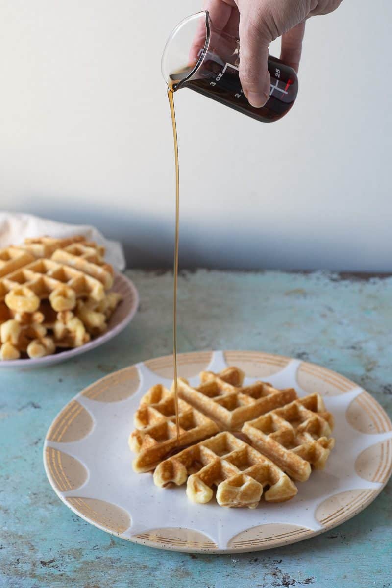 Pouring maple syrup onto a buttermilk waffle