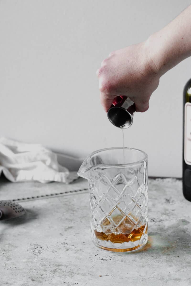 Pouring an ounce of rye into a mixing glass