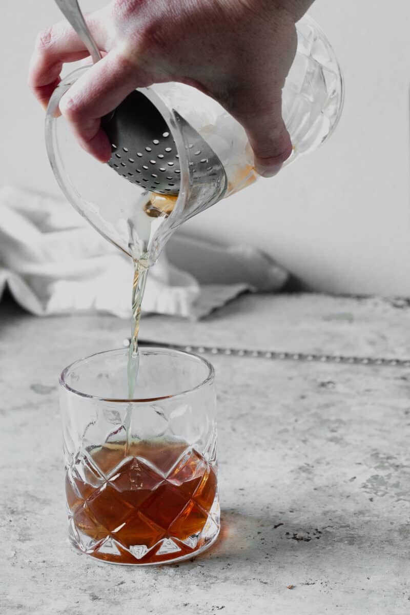 Straining a Manhattan cocktail into a glass