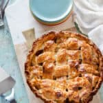 Apple Pie with a lattice top crust on a serving board with a stack of dessert plates next to it