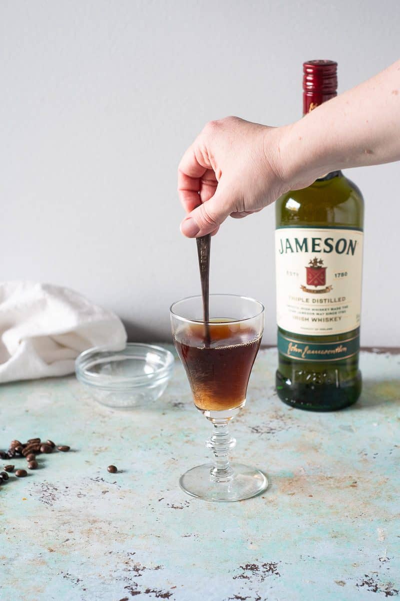 Stirring sugar into hot coffee in an Irish coffee glass