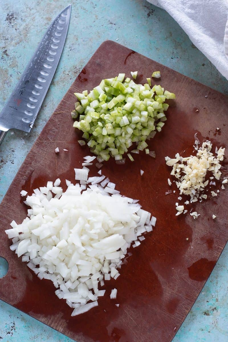Minced onion, celery, and garlic on a cutting board