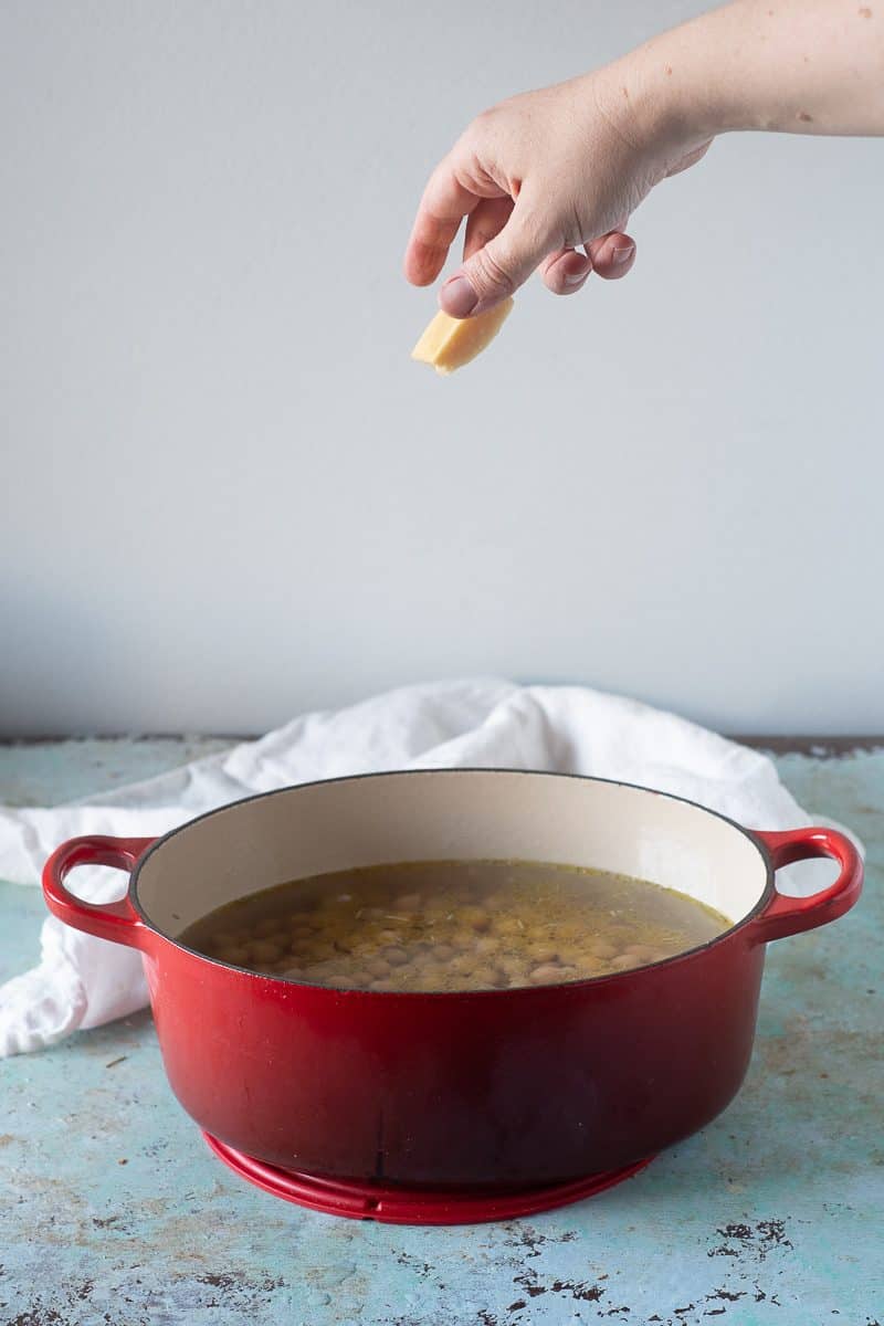 Parmesan rind being dropped into a pot of chickpeas