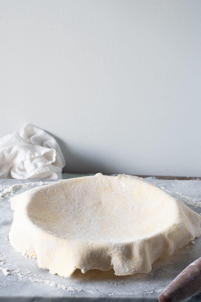 Pie crust dough draped over a pie pan