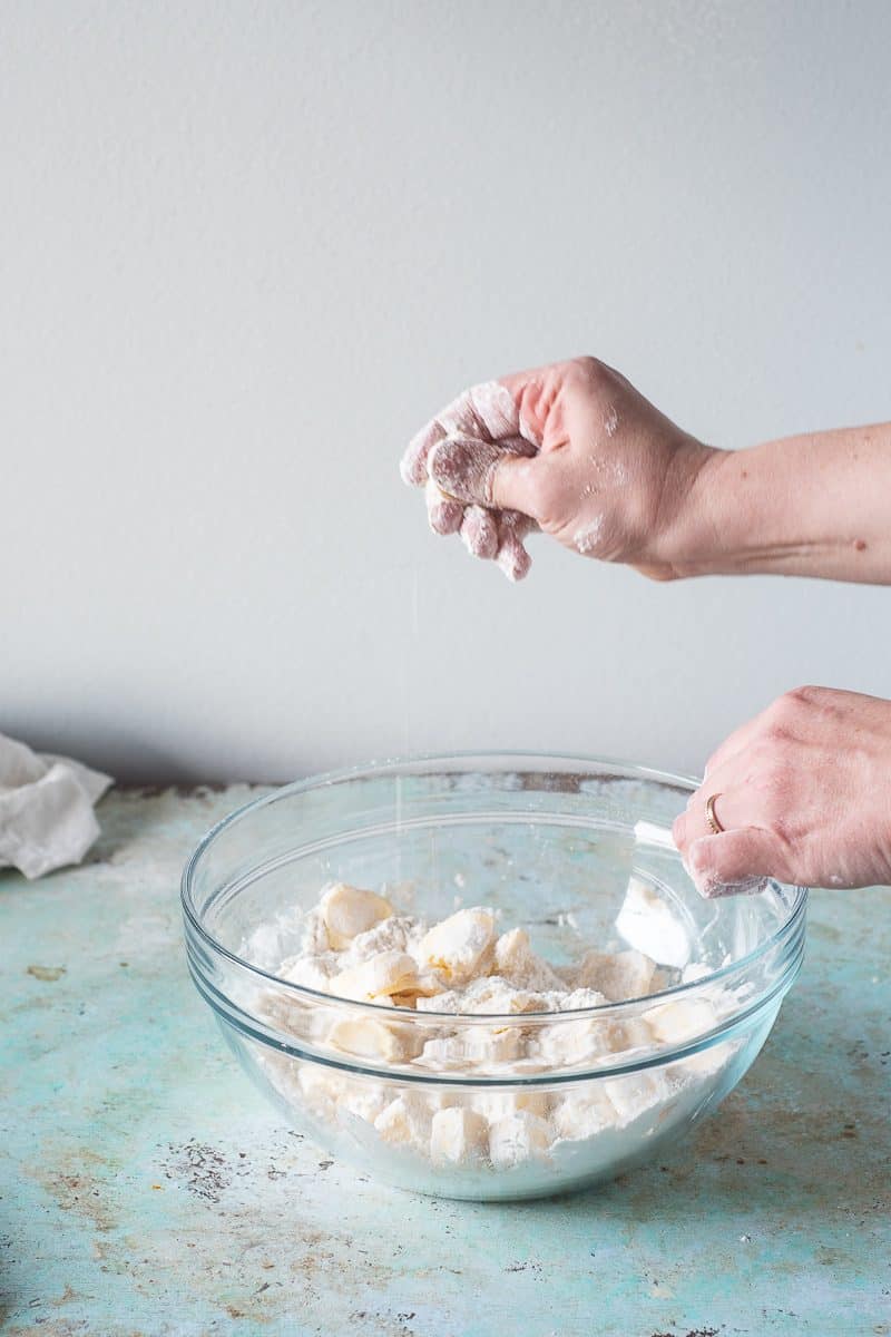 Squeezing a cube of butter between fingers to smush it flat