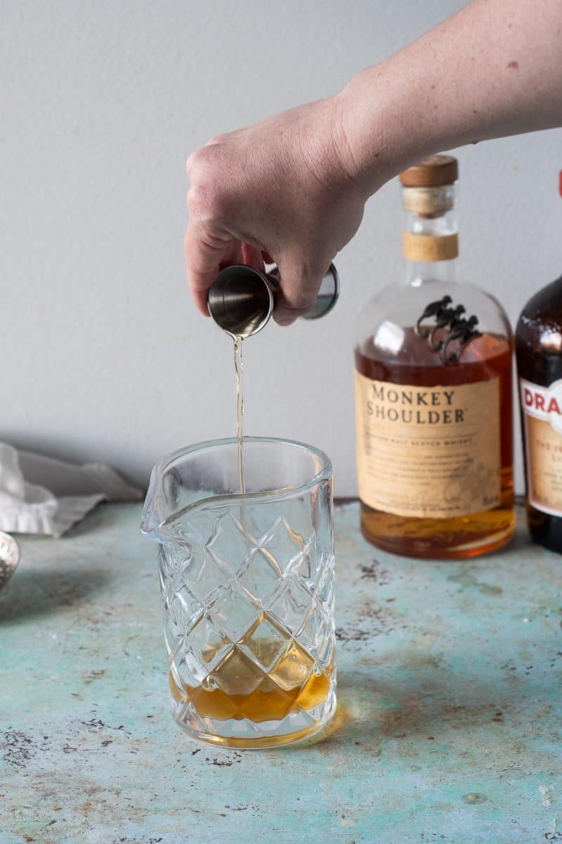 Pouring Scotch into a mixing glass