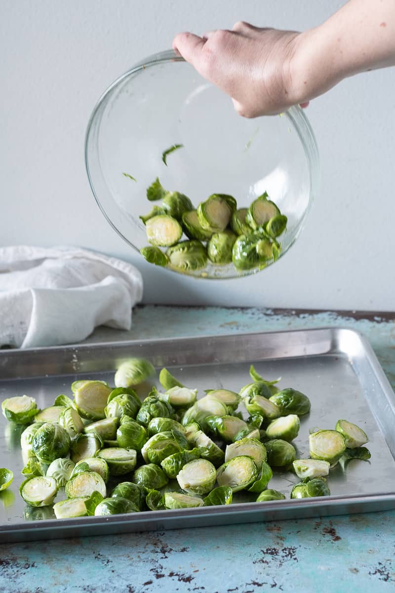 Brussels sprouts being added to a sheet pan