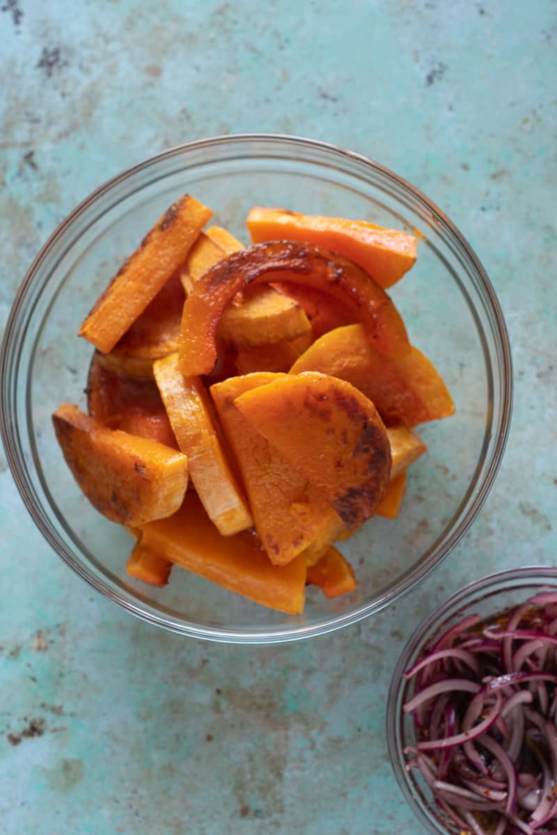 Roasted butternut squash slices in a bowl and pickled onions in agrodolce in a separate bowl
