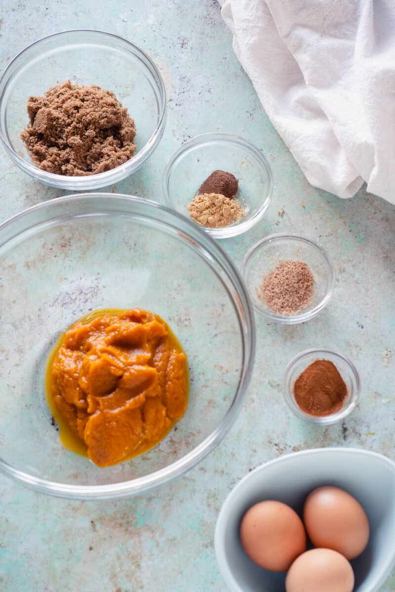 Bowls of brown sugar, spices, eggs, and pumpkin puree