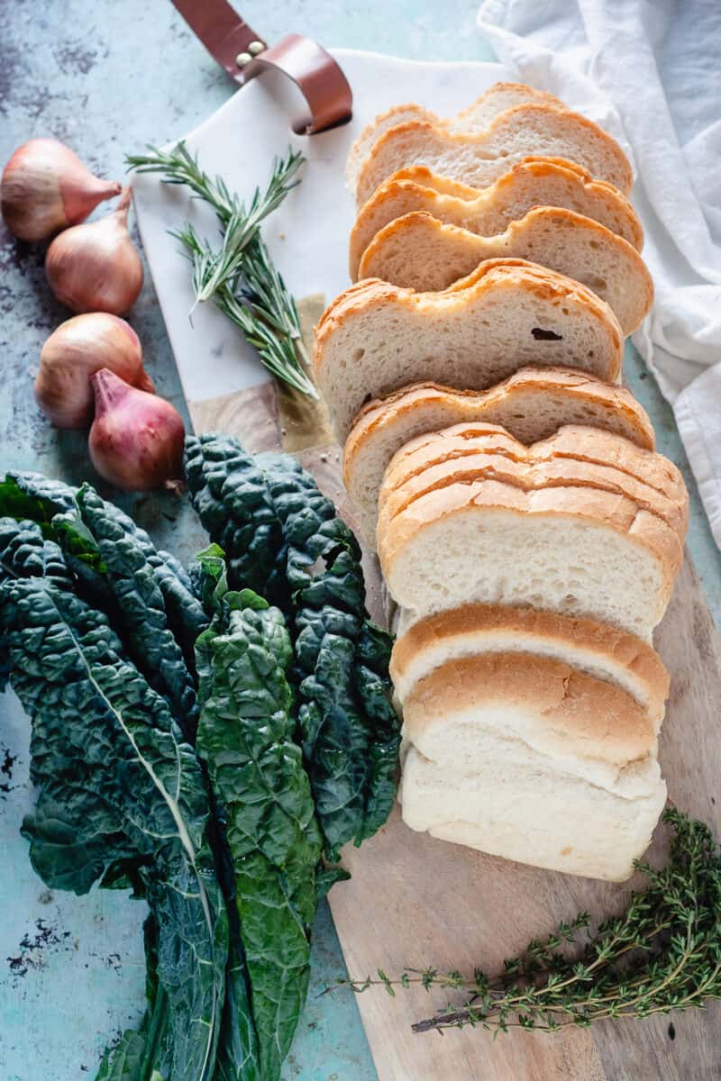 Kale, shallots, rosemary, and bread on a cutting board