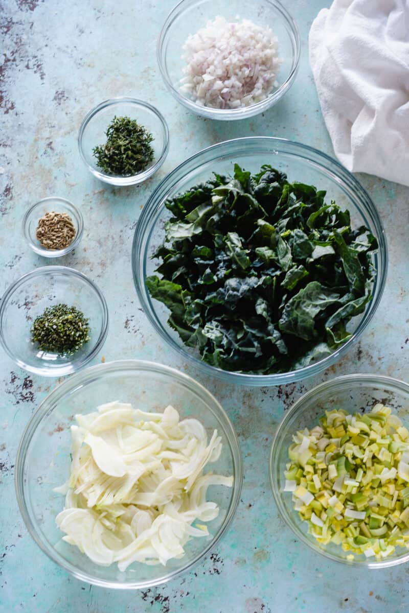 Bowls of sliced kale, fennel, leeks, shallots, and herbs