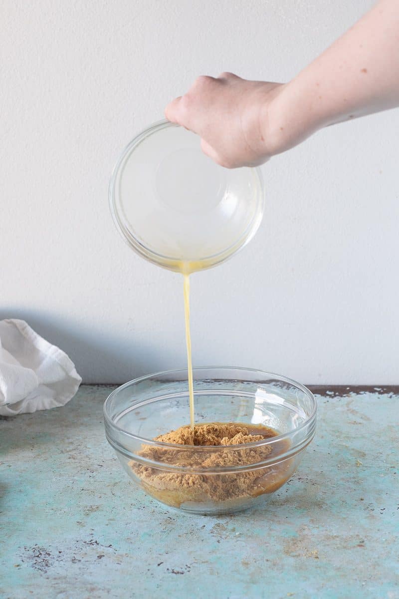 Pouring melted butter into gingersnap cookie crumbs