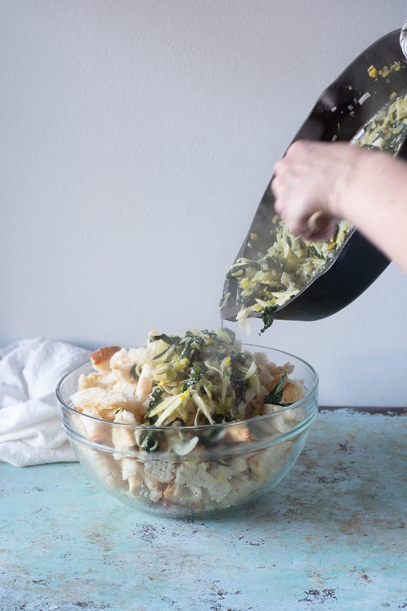 Adding vegetable mixture to bread pieces in a bowl