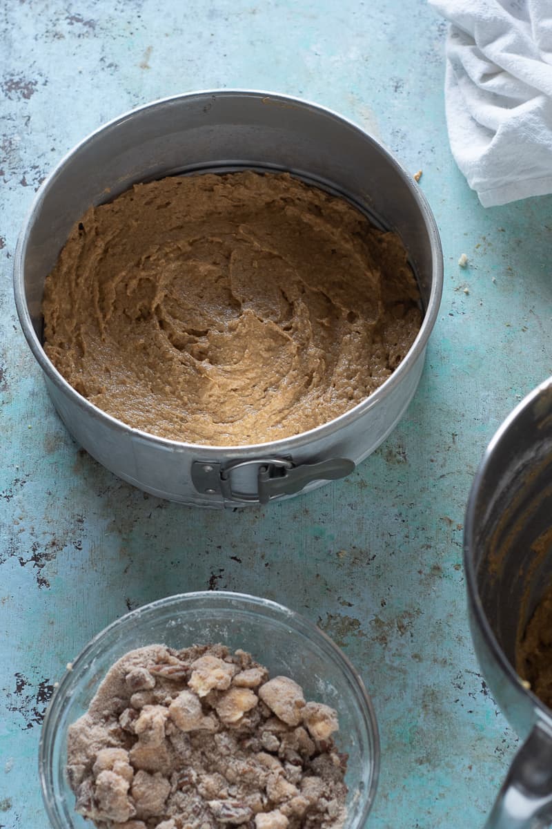 Cake batter spread in a cake pan with brown sugar pecan streusel next to it