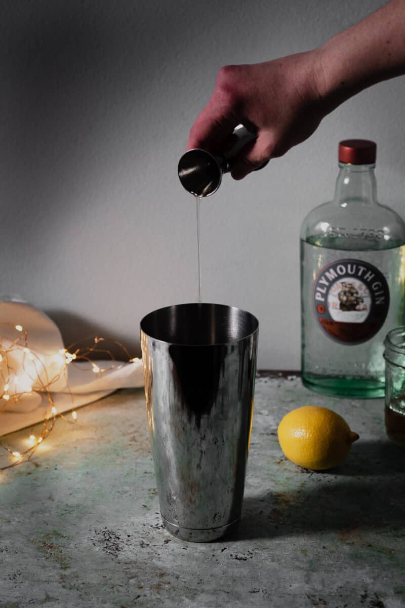 Hand pouring gin into cocktail shaker