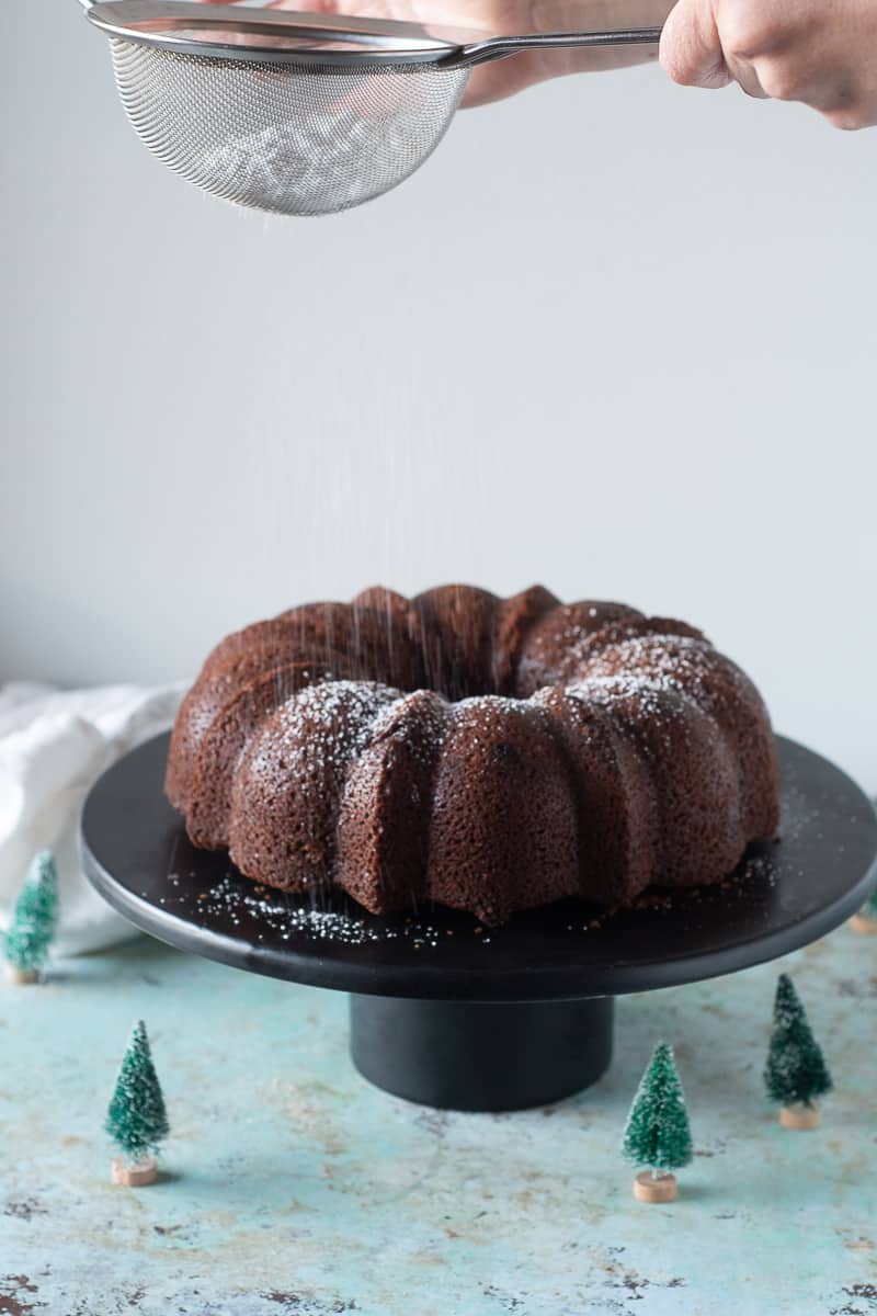 Gingerbread Bundt Cake being dusted with powdered sugar