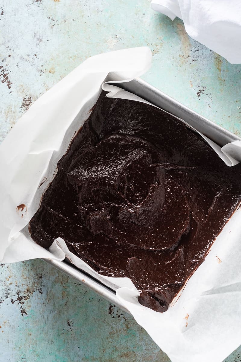 Brownie batter in a parchment-lined pan