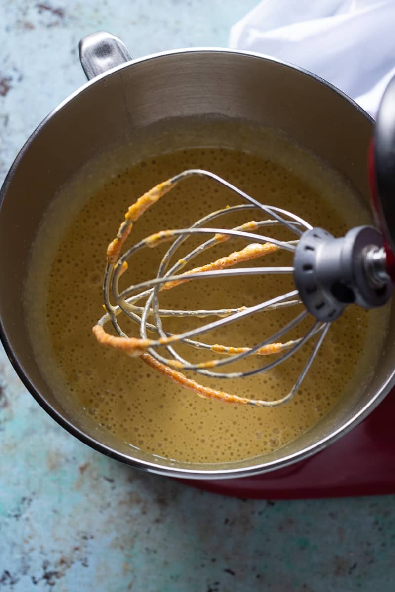 Whisk attachment of a stand mixer over orange cake batter