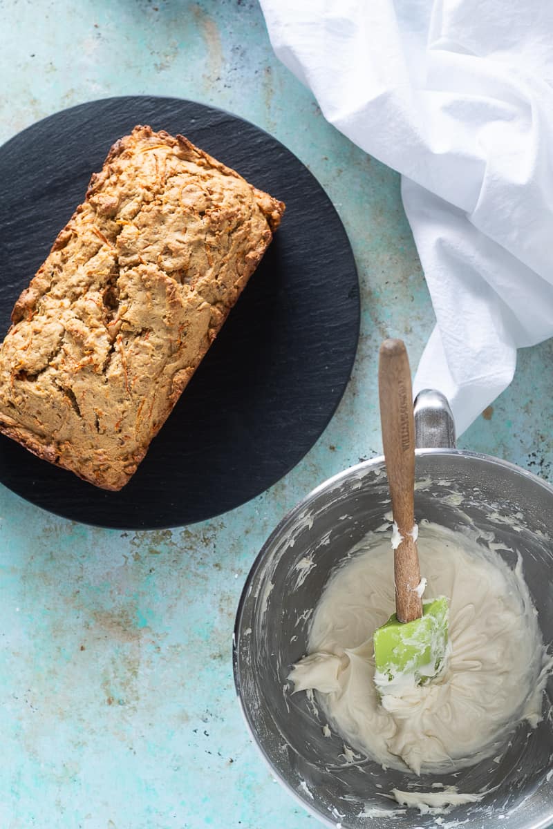 Carrot loaf cake, unfrosted, with cream cheese frosting in a bowl