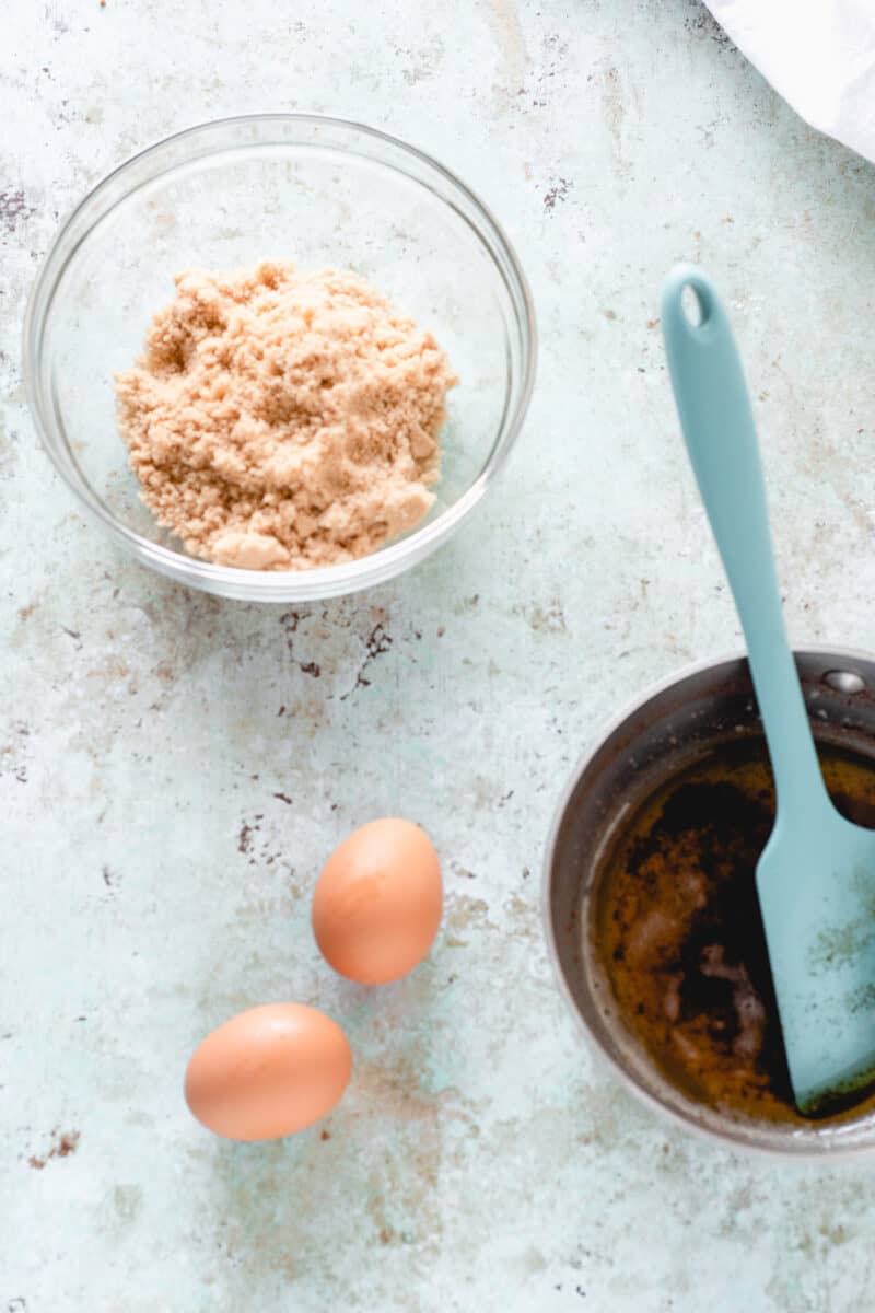 Brown sugar in a bowl, eggs, brown butter in a pan