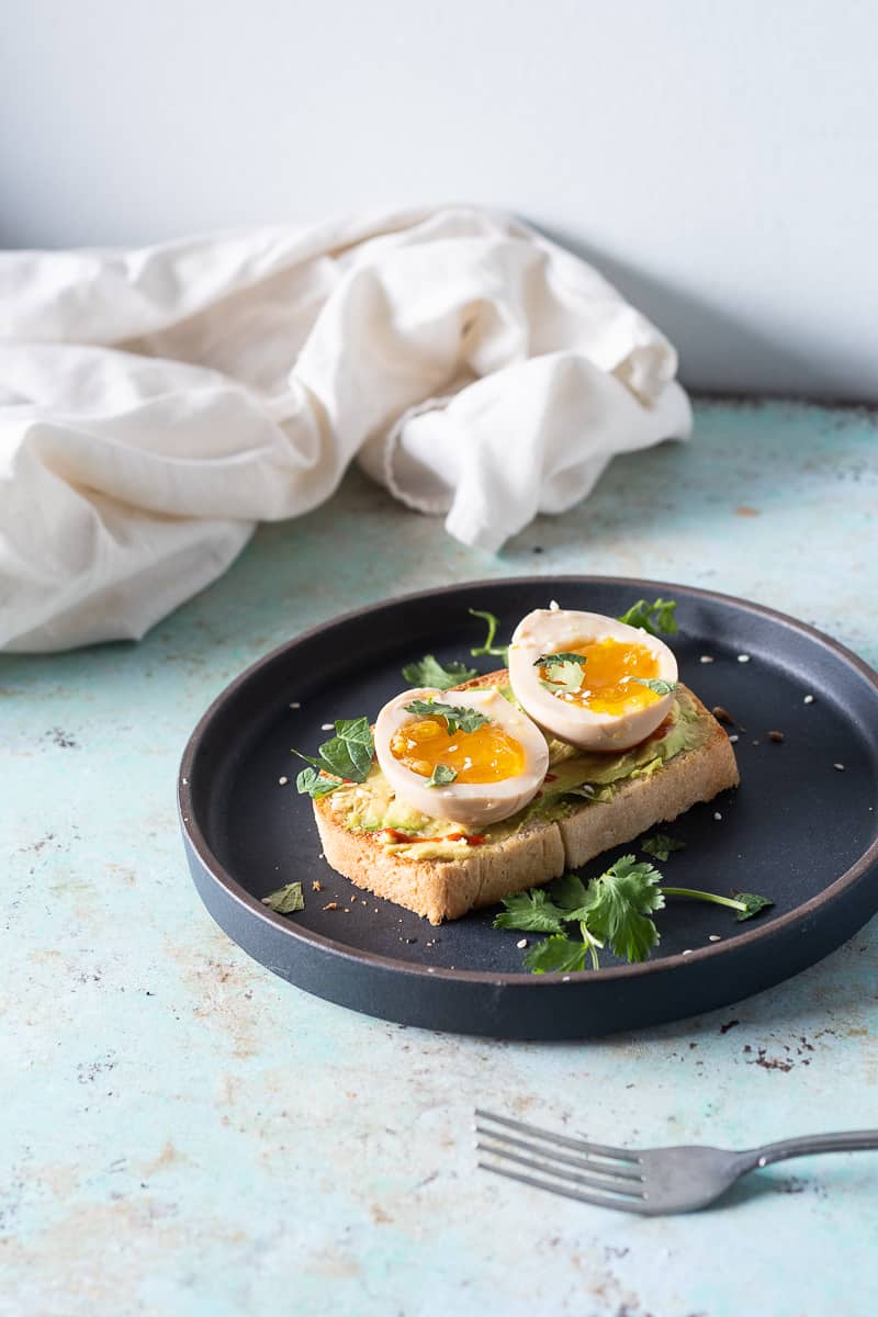 Ramen eggs on avocado toast with sriracha and herbs