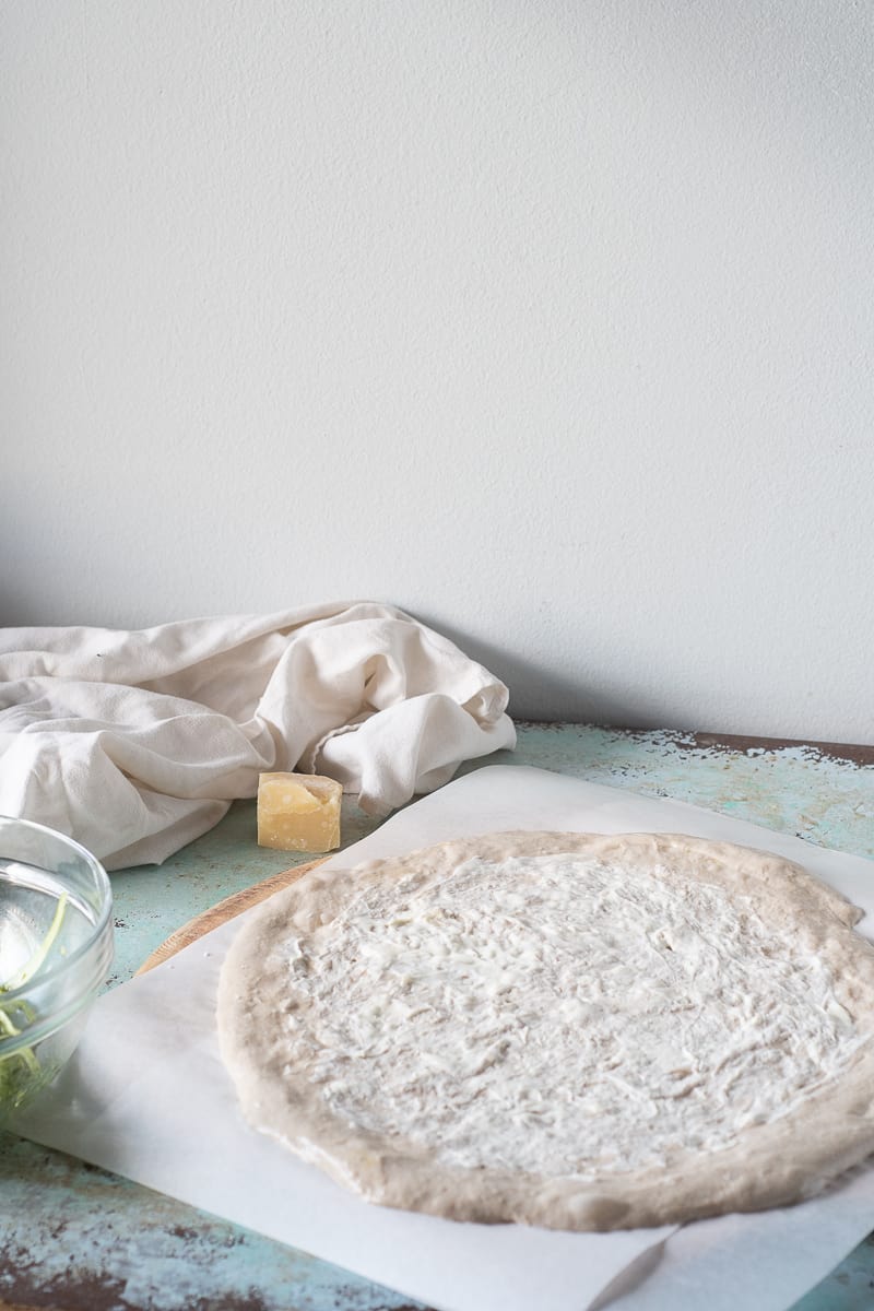 Unbaked pizza dough stretched out and smeared with crème fraîche