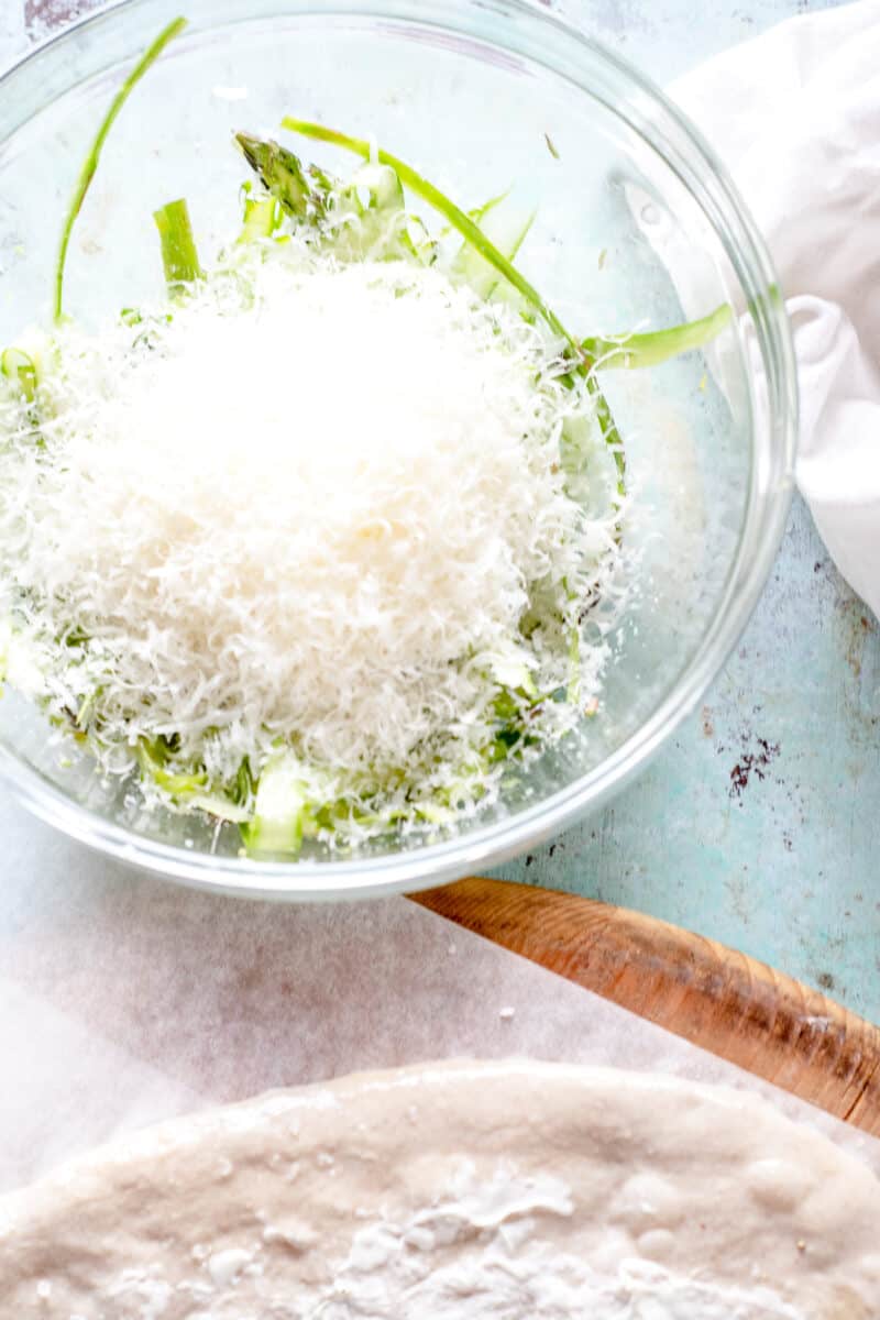 Grated parmesan on shaved asparagus in a bowl