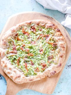 Asparagus pizza on a wooden peel