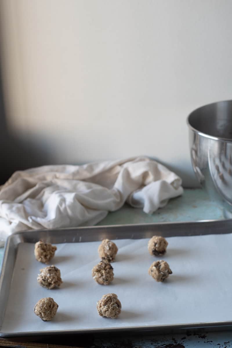 Scoops of oatmeal raisin cookie dough on a parchment-lined sheet pan