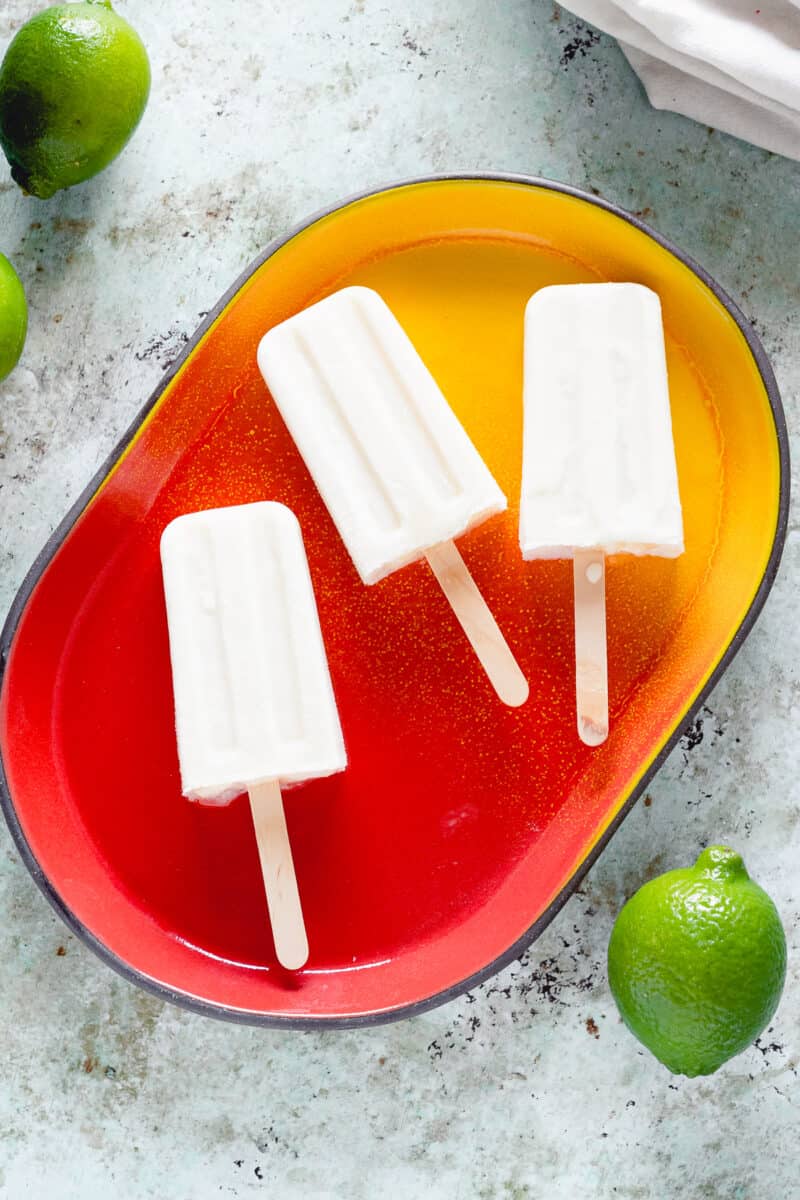 Coconut Lime Popsicles on red and yellow oval tray