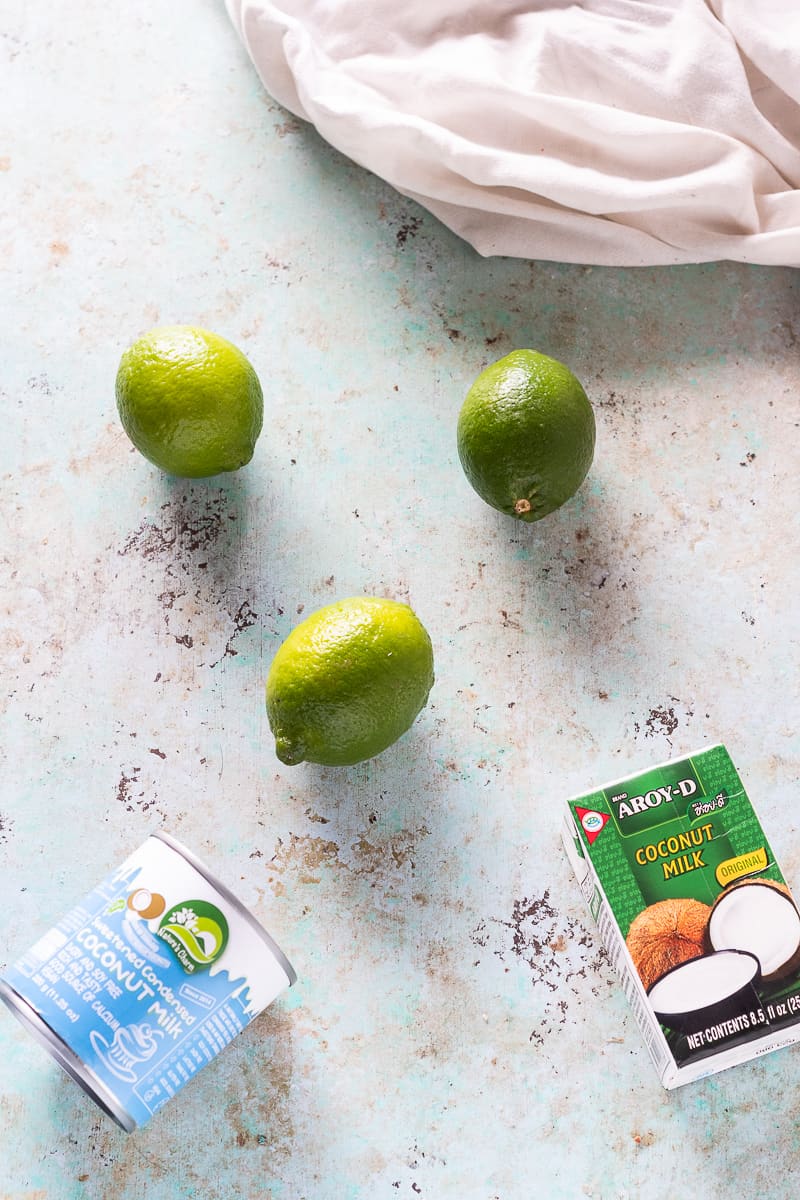 Limes, a can of sweetened condensed coconut milk, a box of coconut milk on a blue background