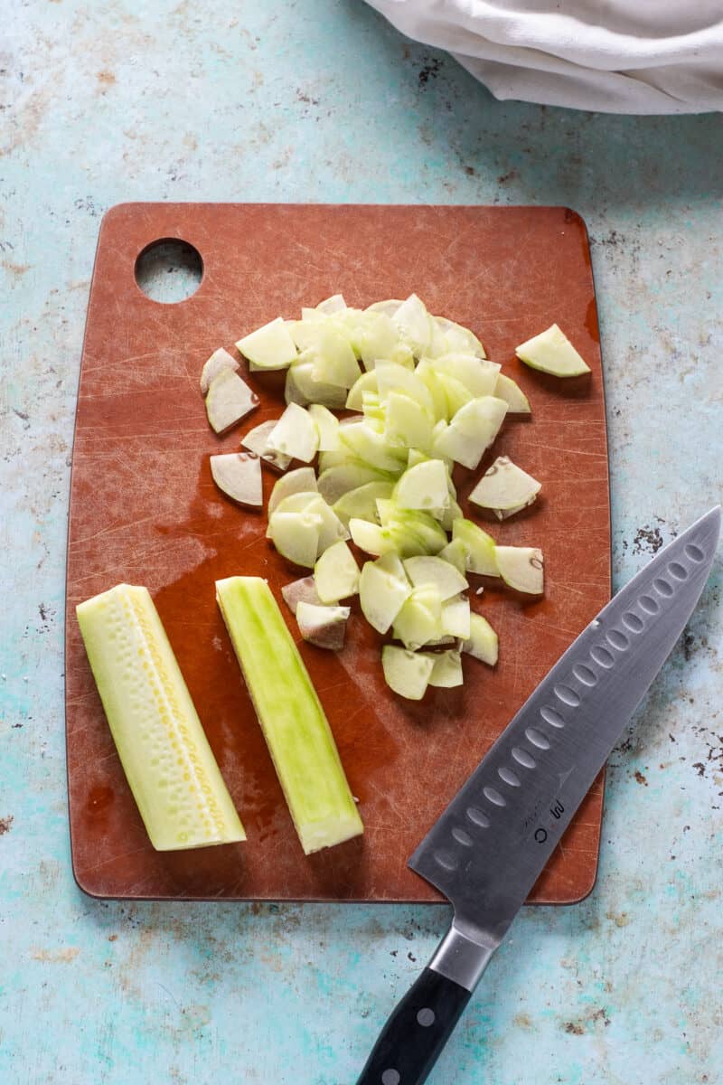 Sliced cucumbers on a cutting board with a chef's knife alongside