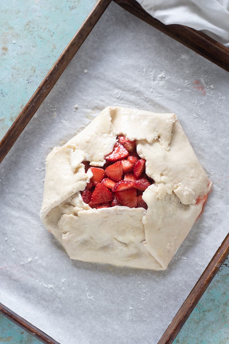 Unbake strawberry galette on parchment on a baking sheet