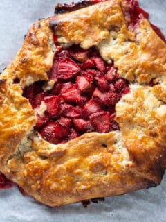 Strawberry galette on parchment paper on a sheet pan, overhead shot