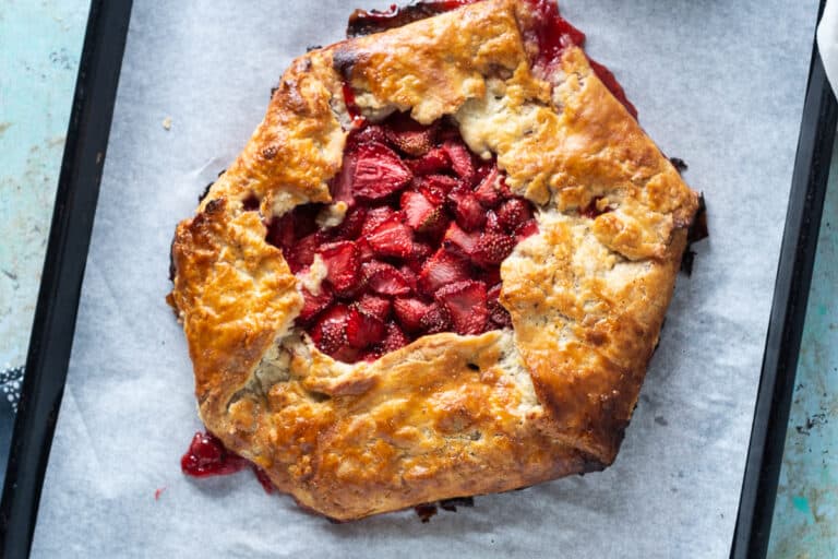 Strawberry galette on parchment paper on a sheet pan, overhead shot